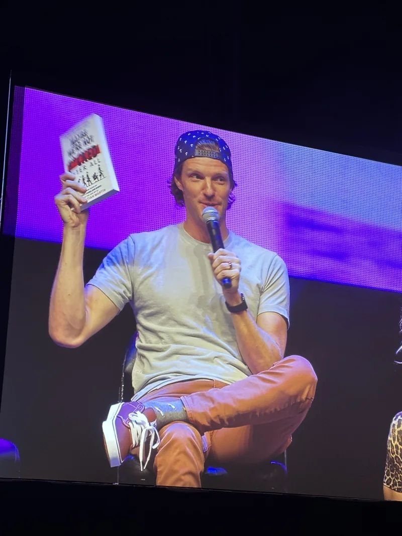 Christian on stage holding his book